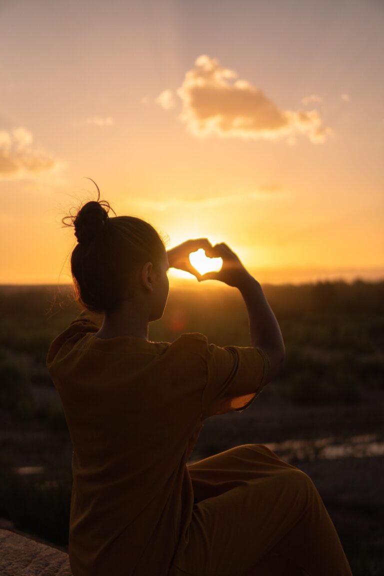 Eine Frau steht vor einem Sonnenaufgang.