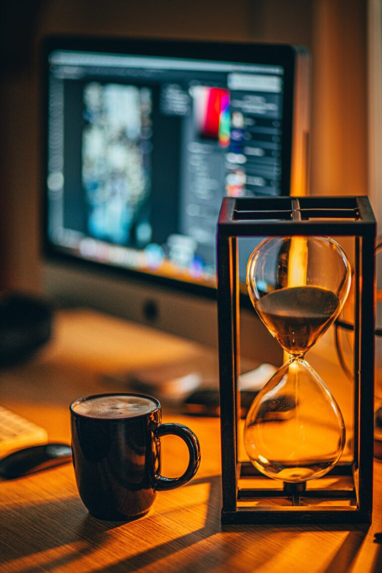 Eine Sanduhr steht neben einem Computer.