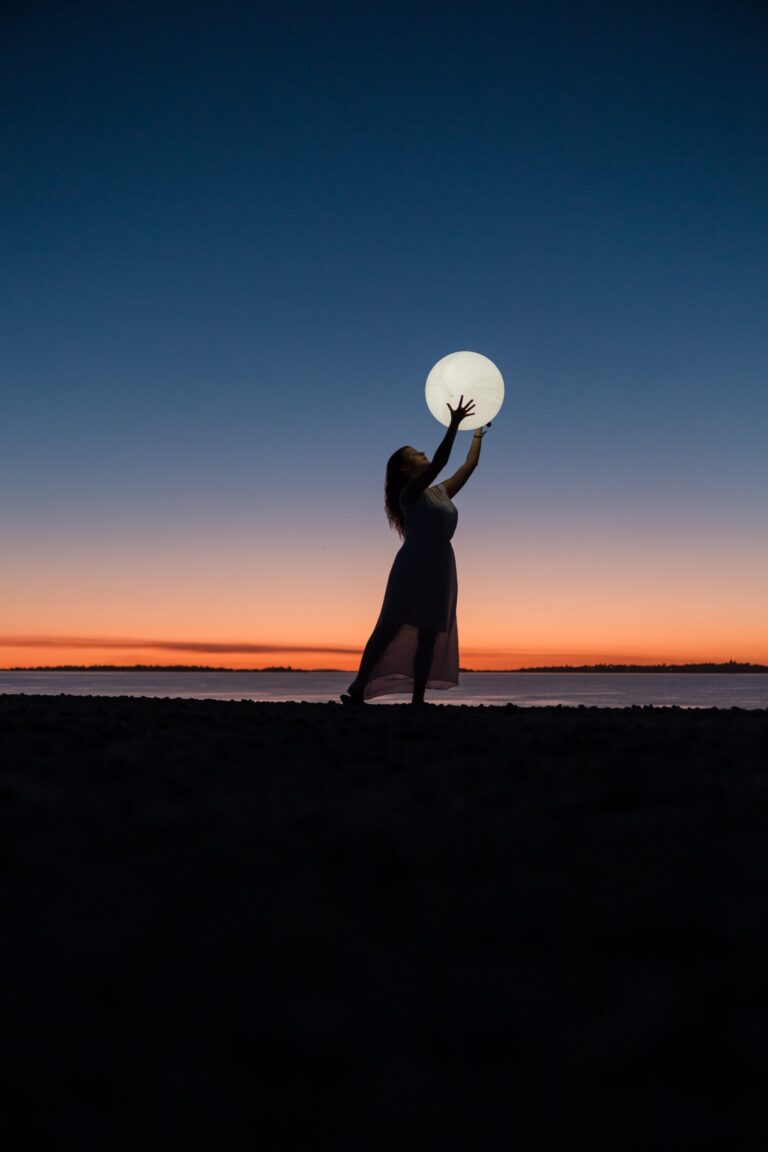 Eine Frau greift nach dem Vollmond, der tief am Himmel hängt.