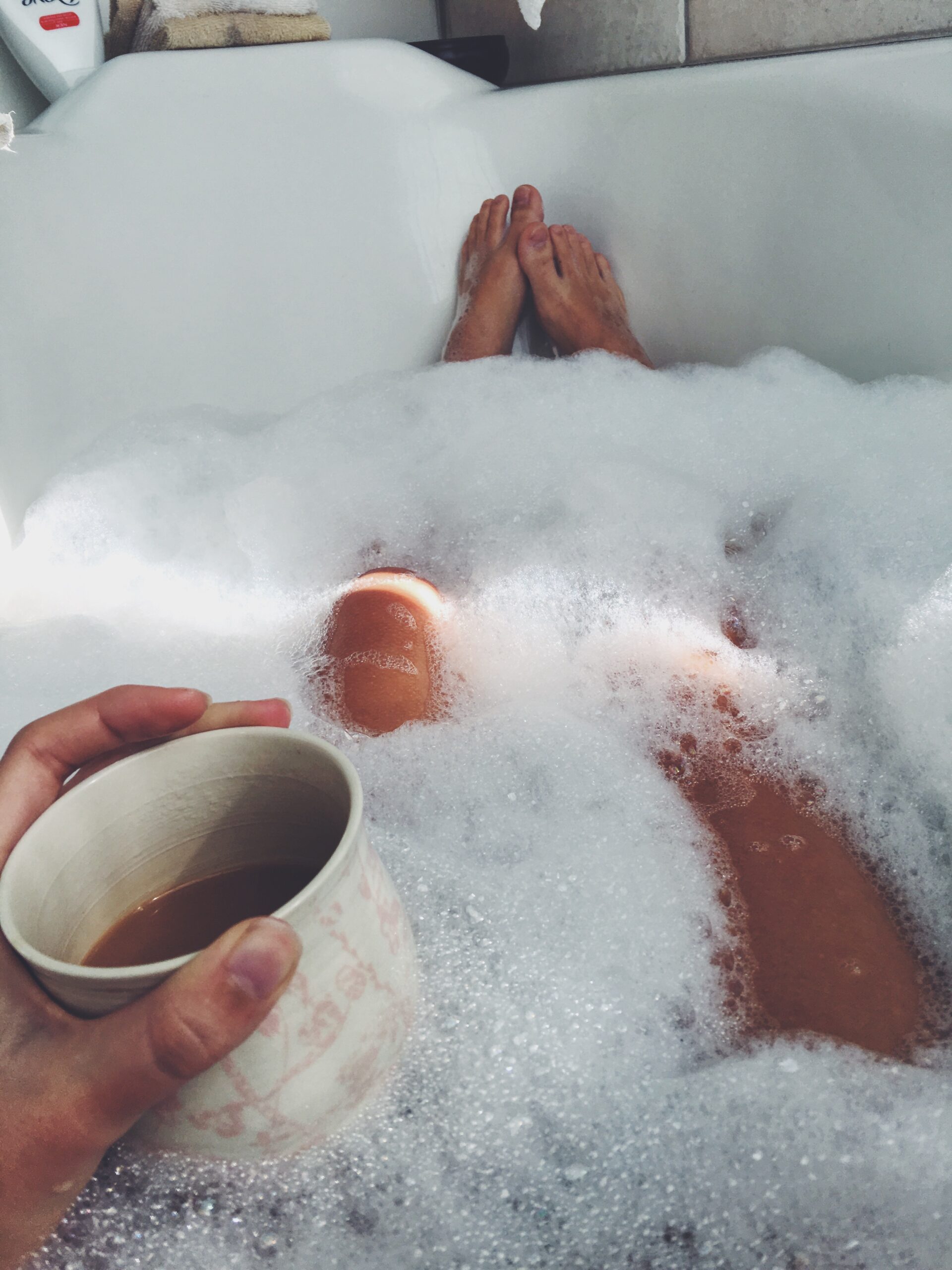 Eine Frau mit Kaffeetasse in der Badewanne.