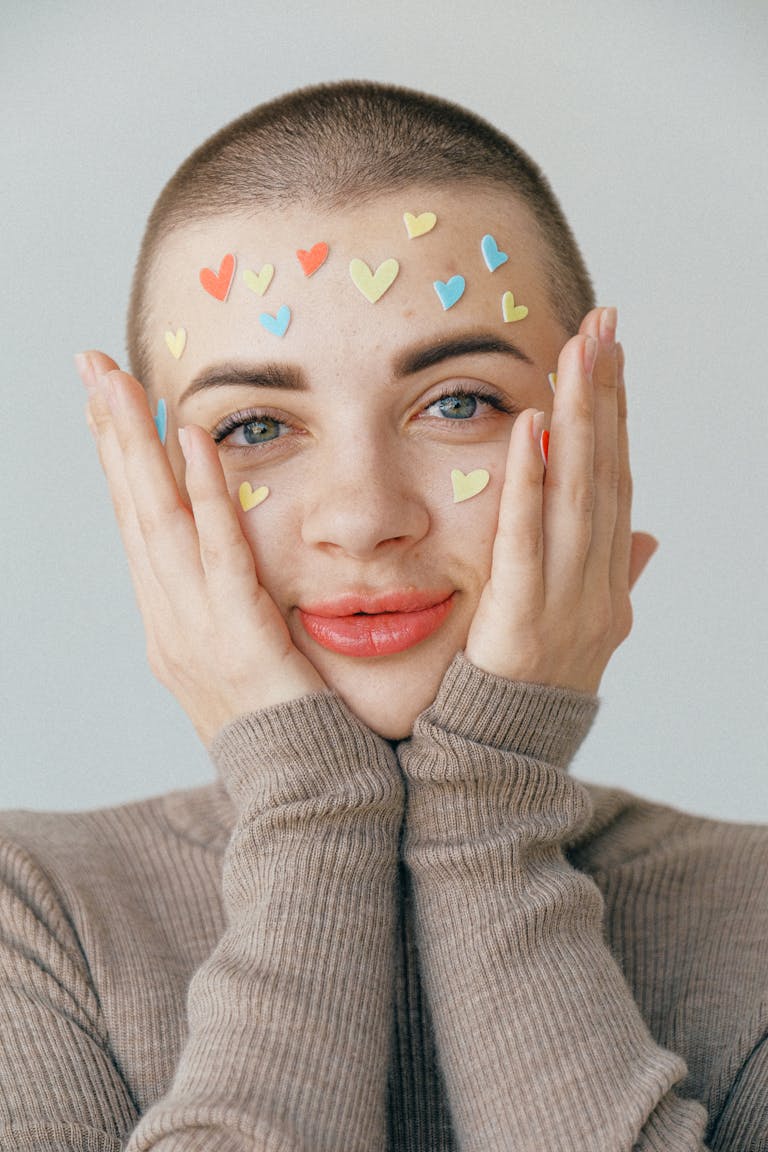 A bright portrait of a smiling person with heart stickers on their face. Ideal for Valentine's themes.